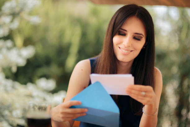 mulher feliz abrindo um envelope recebendo boas notícias - opening mail envelope greeting card - fotografias e filmes do acervo
