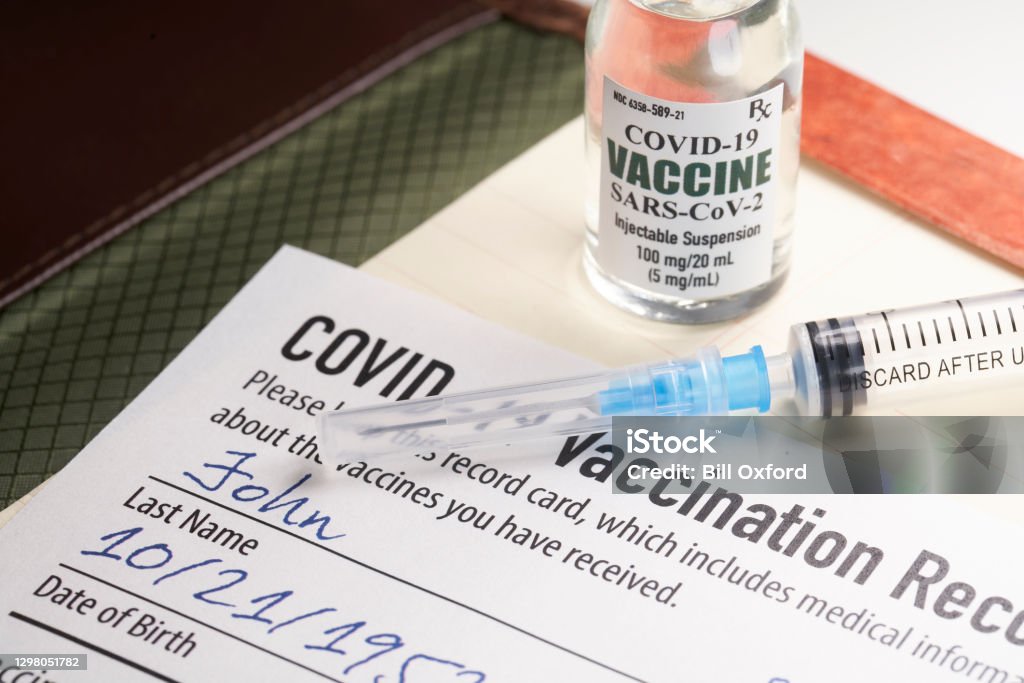 Covid-19 vaccination record card with syringe and vial COVID-19 Vaccine Stock Photo