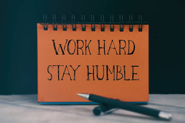 istock Work hard stay humble, the text is written on a orange notebook, pen and are next to it 1298054256