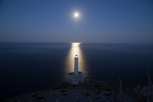 Lighthouse of Capo d'Otranto lit by the moonlight on a clear night of a summer in Puglia, Italy