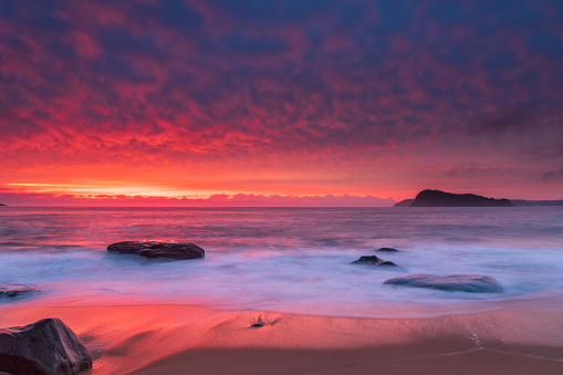 Colourful sunrise seascape with high cloud filled sky from North Pearl Beach on the Central Coast, NSW, Australia.