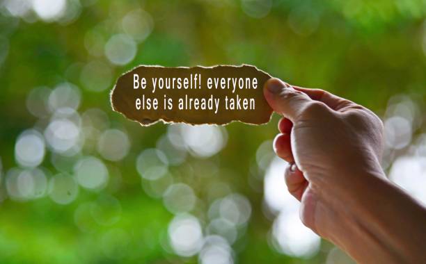 istock Text Written On Hand Holding Torn Paper With Blurred Green Background. Be yourself concept 1298073921