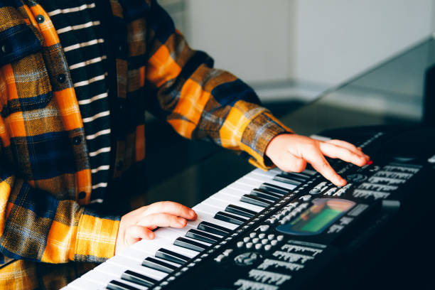 крупным планом руки ребенка курсирующих электрическое пианино - электропиано стоковые фото и изображения