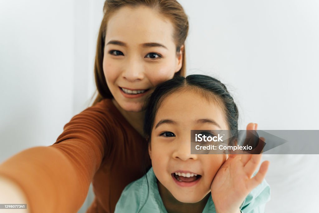 Happy Asian mother with cute girl waving towards camera Mother Stock Photo