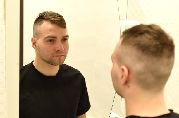 istock Young man looking in the mirror at his reflection in a bathroom 1298077601