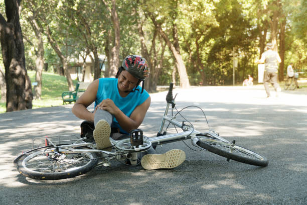 i ragazzi motociclisti cadono dalla bici e tengono il ginocchio dal dolore nel parco. incidente uomo nello sport. - bmx cycling bicycle cycling sport foto e immagini stock