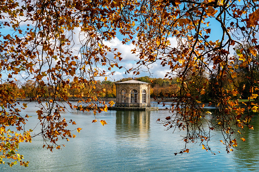 Fontainebleau, France - 2020 26 October: Pavilion in the middle of the Carp Pond with the royal castle of Fontainebleau in the background. Shot in autumn on a cloudy day.