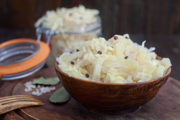 Homemade sauerkraut with black and red pepper in wooden bowl on rustic background stock photo