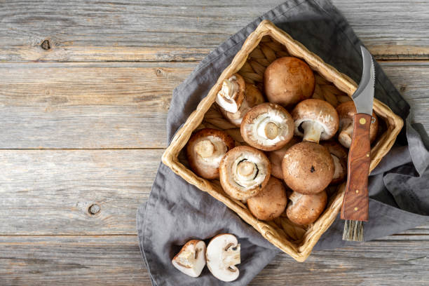 istock Mushrooms in a basket on the brown wooden kitchen table. Champignons 1298085355