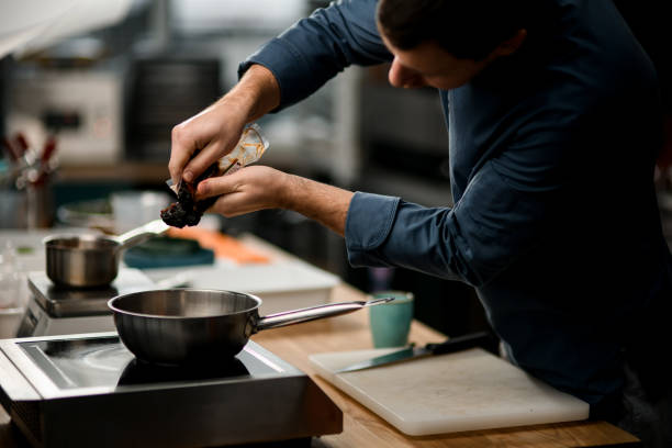 istock man chef holds package with product and puts it on frying pan 1298086884