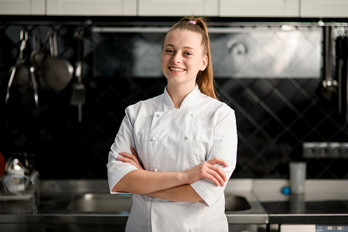 joven hermosa mujer sonriente chef con los brazos cruzados en la cocina photo