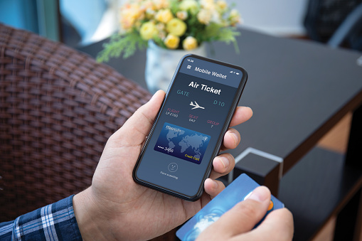 male hands holds phone with airplane ticket application airlines on the screen and credit card in the room