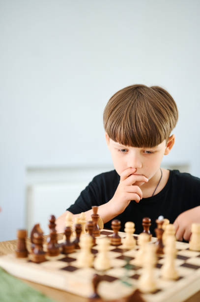 istock Smart preschool caucasian boy playing chess at home 1298090451