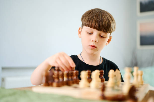 istock Smart preschool caucasian boy playing chess at home 1298090563