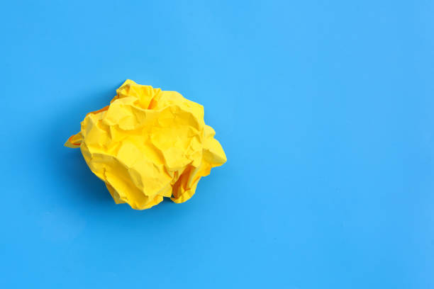 istock Crumpled yellow paper ball on blue background. 1298091779