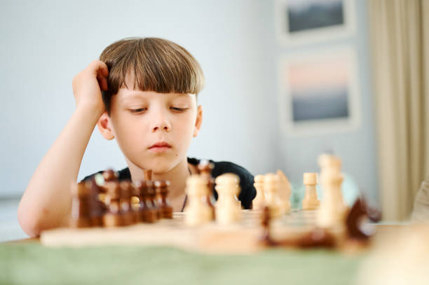 istock Smart preschool caucasian boy playing chess at home 1298091786