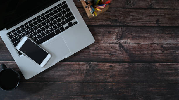 istock Top view of laptop computer, smart phone and notebook on wooden table. Copy space for text message or information content. 1298092705