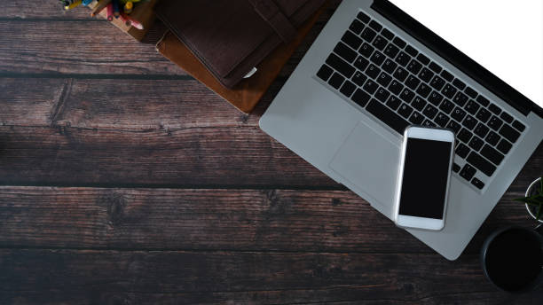 istock Top view of freelance workspace with laptop computer, smart phone and notebook on wooden table. Copy space for text message or information content. 1298092945