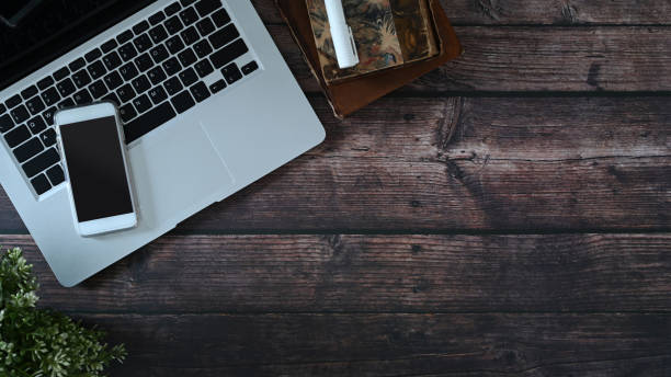 istock Top view of hipster workplace with laptop computer, smart phone and notebook on wooden table. Copy space for text message or information content. 1298092954