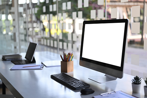 Vista lateral del ordenador con pantalla en blanco y tableta en la estación de trabajo moderna. photo