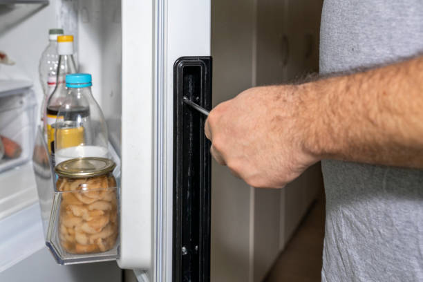 istock a man adjusts the refrigerator door with a screwdriver 1298095130