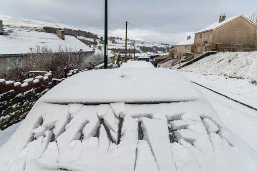 A car under the snow. Snow and ice on cars after extreme snowfall in the town. Winter town scene. The car on the street is covered in ice rain. Snow-covered vehicles.