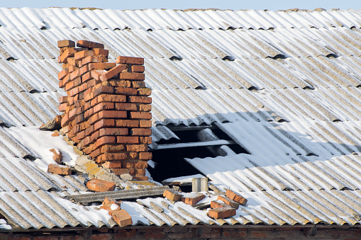 Old destroyed chimney on the roof of the house in winter. Abandoned buildings.
