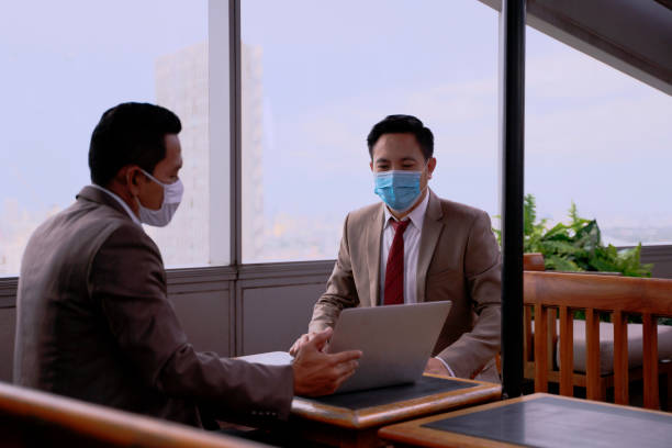 istock Business employees are using computer notebook and wearing face mask. 1298096761