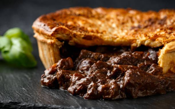 britische sintinder mit zwiebel, weinsoße auf rustikalem steinbrett - beef pie stock-fotos und bilder