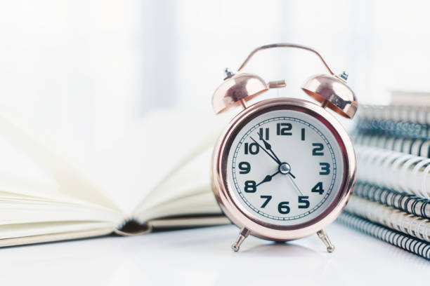 istock Bell alarm clock with blurred books for time management for study and work concept 1298102603