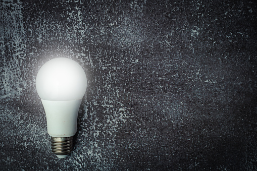 Glowing LED light bulb on dark grunge background for energy savings concept