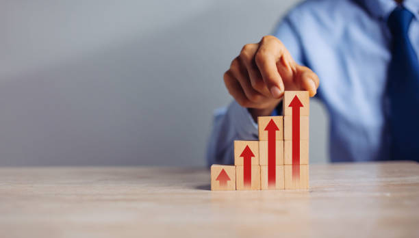 istock businessman hand  arranging wood block stacking as step stair with arrow up.concept for business growth success process. 1298103273