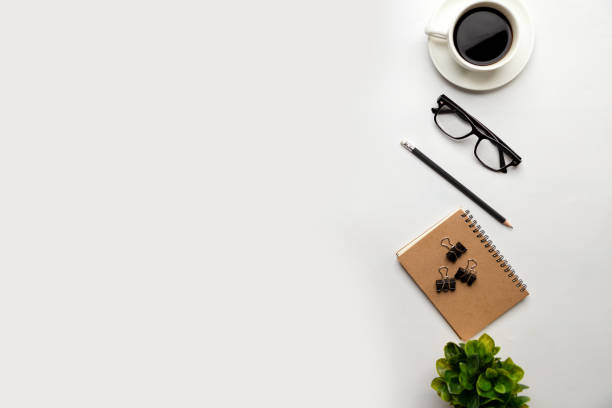 istock Flat lay, top view office table desk. Workspace with blank, office supplies, pencil, green leaf, and coffee cup on white background. 1298103385