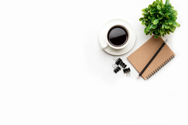 istock Flat lay, top view office table desk. Workspace with blank, office supplies, pencil, green leaf, and coffee cup on white background. 1298103491