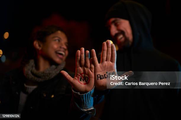 A Young White Man And A Young Black Woman Smiling Showing A Handwritten Message Against Racism Stock Photo - Download Image Now