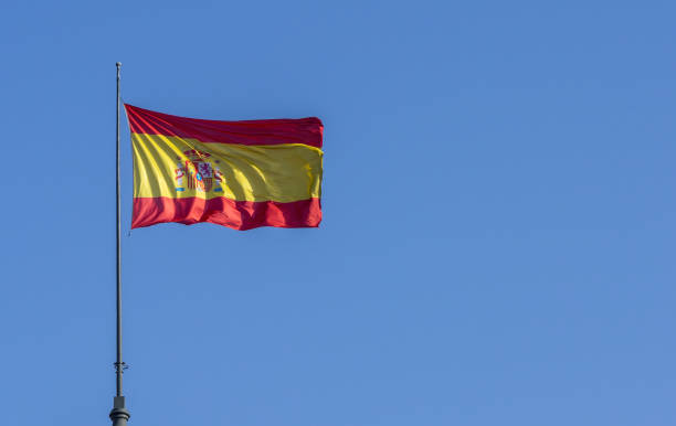 Spanish flag waving on breeze against bright blue sky