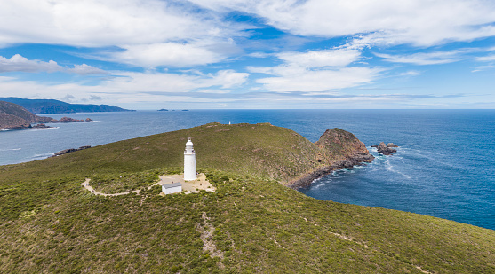 Stunning panoramic high angle aerial drone view of Cape Bruny Lighthouse, a famous destination for tourists visiting Bruny Island, Tasmania, Australia. Lighthouse Bay in the background.