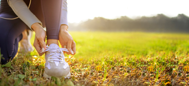 young woman runner tying her shoes preparing for a jog outside at morning