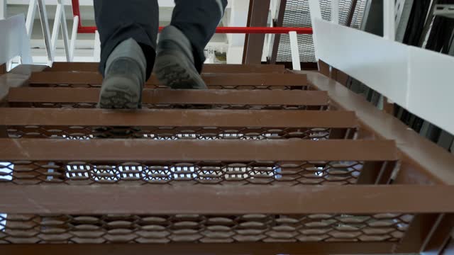 Worker at the factory climbs the iron stairs. bottom view