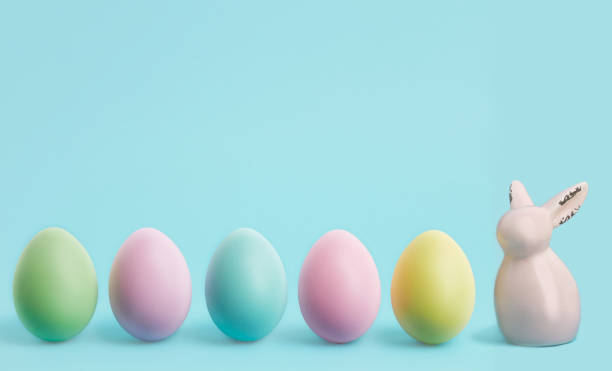 istock Happy Easter banner. colorful easter eggs and rabbit on blue pastel background. Easter greeting card or web border with copy space 1298111573