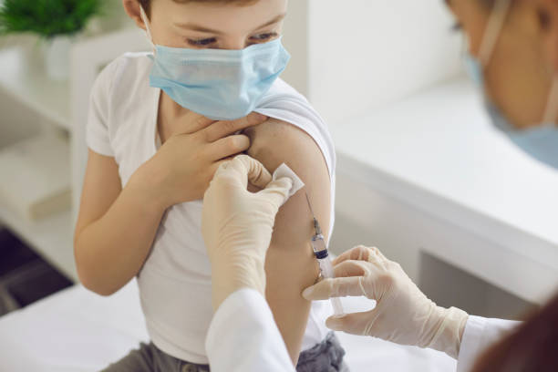 istock Boy in face mask getting flu shot at doctor's office during World Immunization Week 1298112568