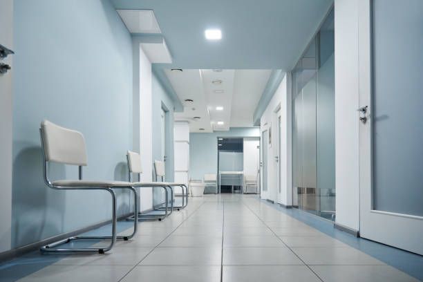 Empty modern hospital corridor, clinic hallway interior background with white chairs for patients waiting for doctor visit. Contemporary waiting room in medical office. Healthcare services concept