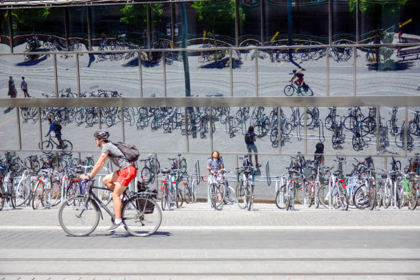 Freiburg im Breisgau, July 8, 2020, Baden-Württemberg, Germany: Glass facade of the modern university library with parked bicycles. The facade reflects the traffic on the street with a car and the tracks of the tram.