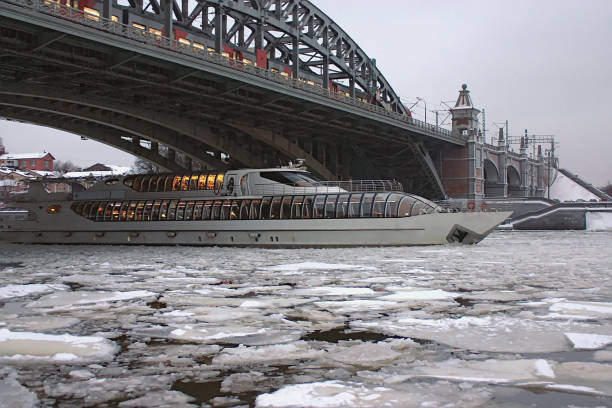 a pleasure boat passes under the bridge on the winter river