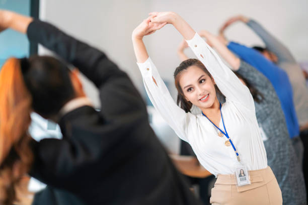 Asian office worker relax and stretching by group exercise before start working every morning in her company stock photo