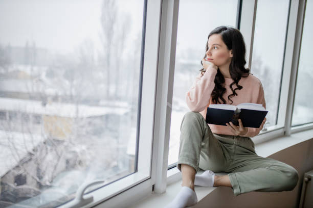 istock Depressed woman reading book at home 1298116464