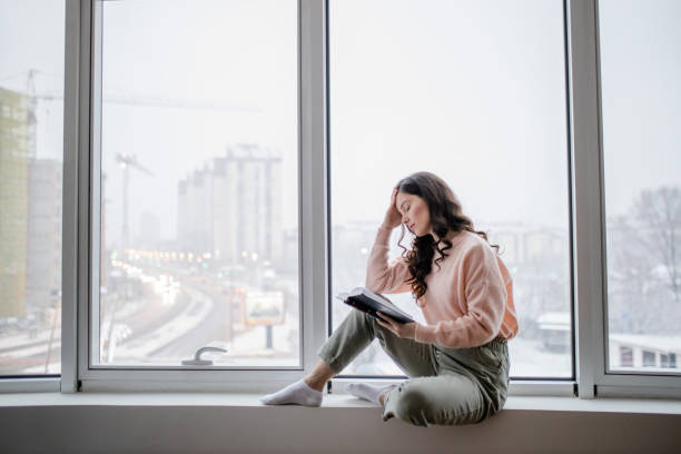 istock Depressed woman reading book at home 1298116552