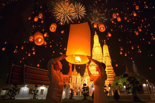Traveler couple enjoy yeepeng floating lantern in loi kratong festival at Arun temple, Bangkok city, Thailand