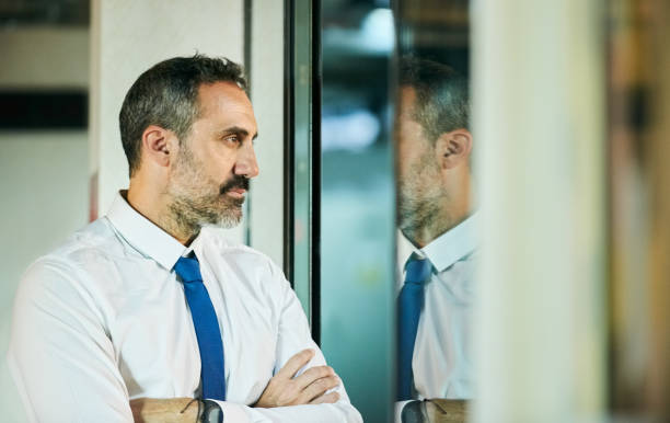 istock Businessman looking thoughtfully out of an office window 1298120612