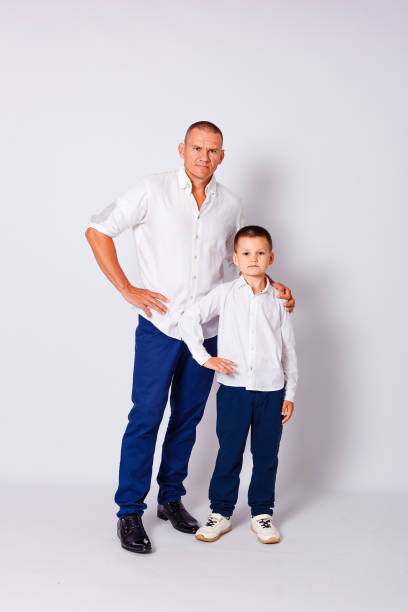 istock Father hugs seven-year-old son by shoulder on white background 1298121598